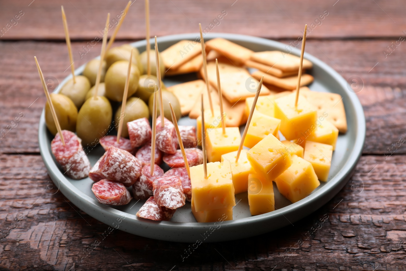 Photo of Toothpick appetizers. Pieces of cheese, sausage and olives on wooden table