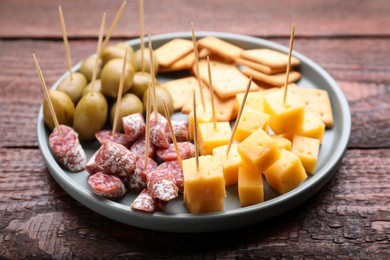 Photo of Toothpick appetizers. Pieces of cheese, sausage and olives on wooden table