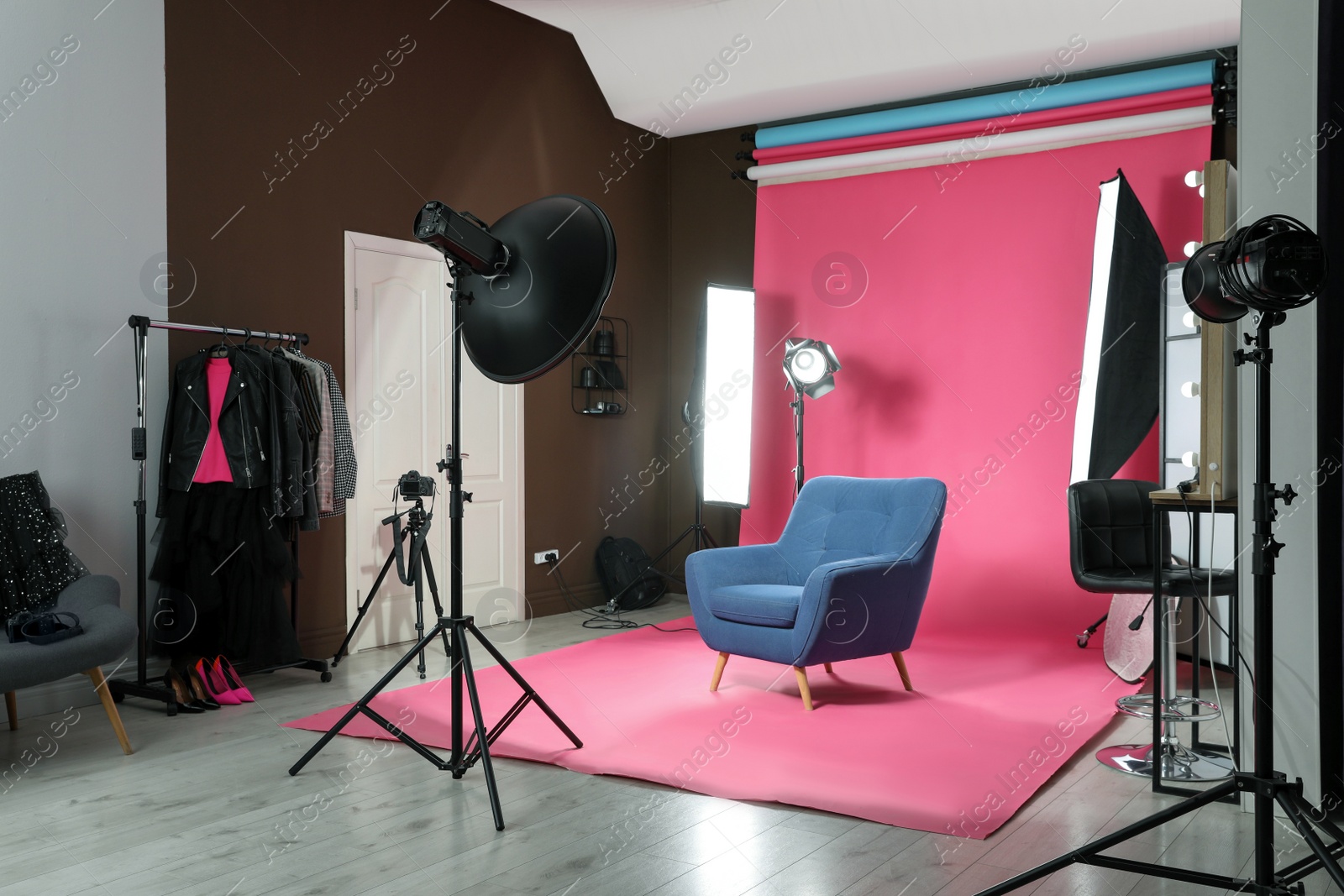 Photo of Stylish blue armchair in photo studio with professional equipment