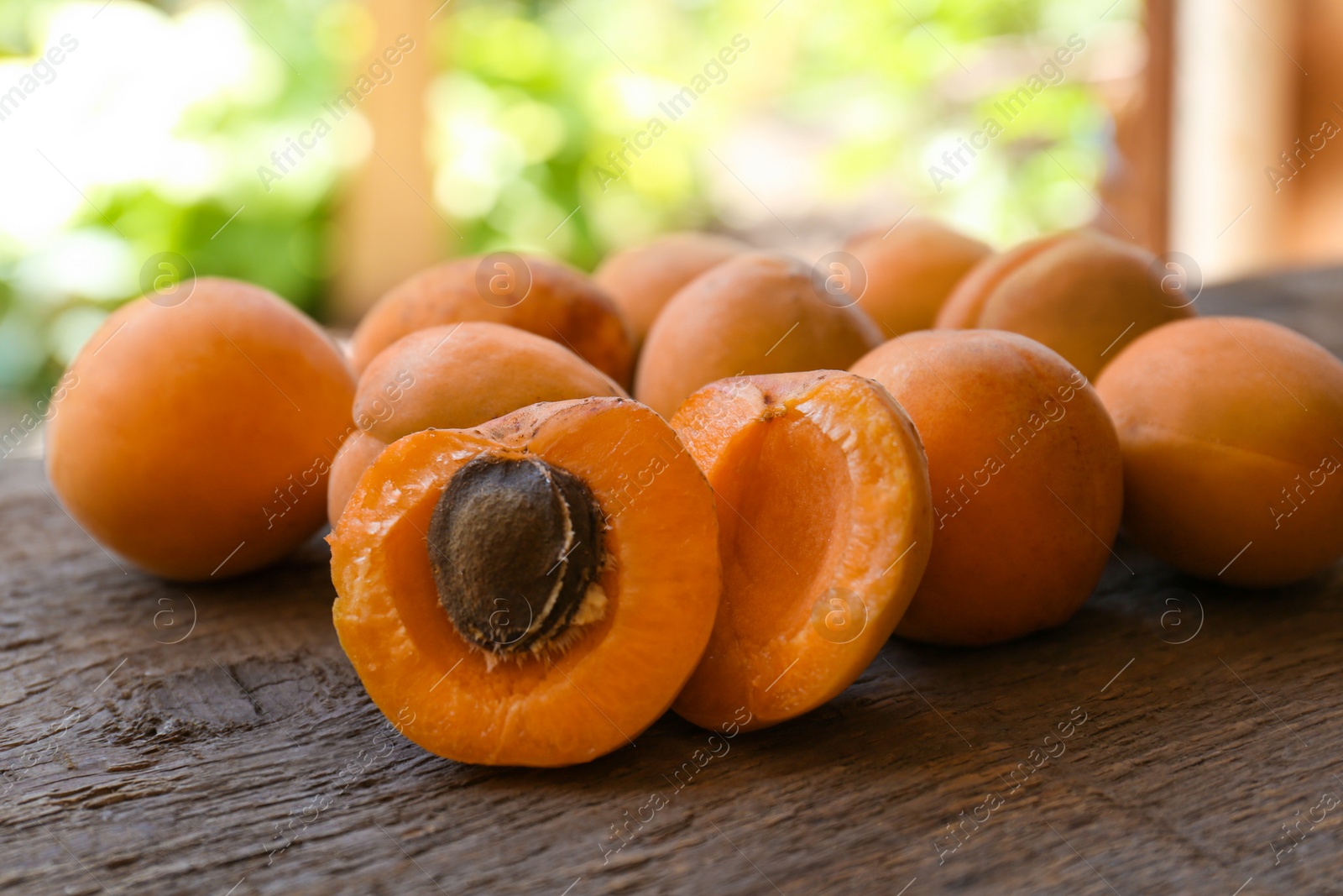 Photo of Delicious ripe apricots on wooden table outdoors, closeup