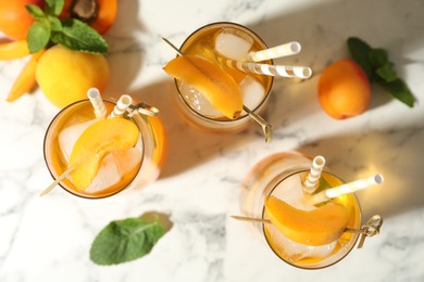 Photo of Delicious refreshing drink with apricot on white marble table, flat lay