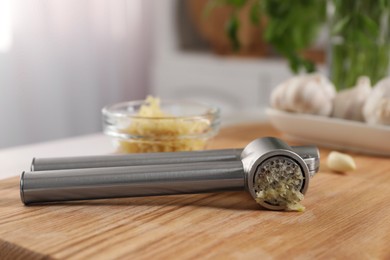 Photo of Garlic press with mince on wooden table in kitchen, closeup