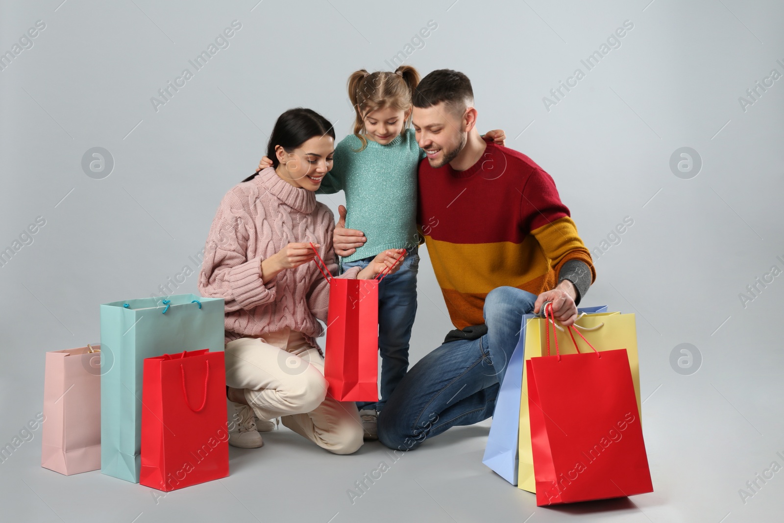 Photo of Happy family with paper bags on grey background. Christmas shopping