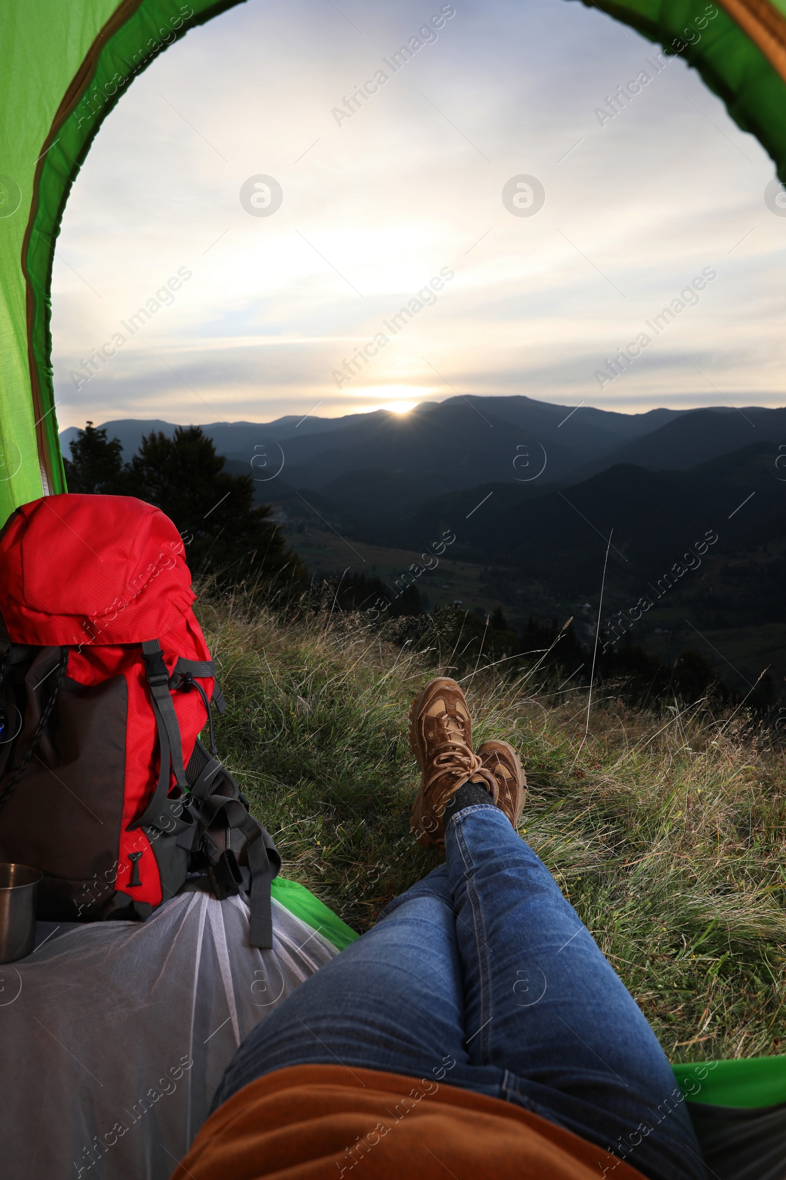 Photo of Woman resting inside of camping tent in mountains at sunset, closeup