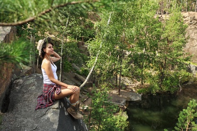 Photo of Young woman on rocky mountain in forest. Camping season