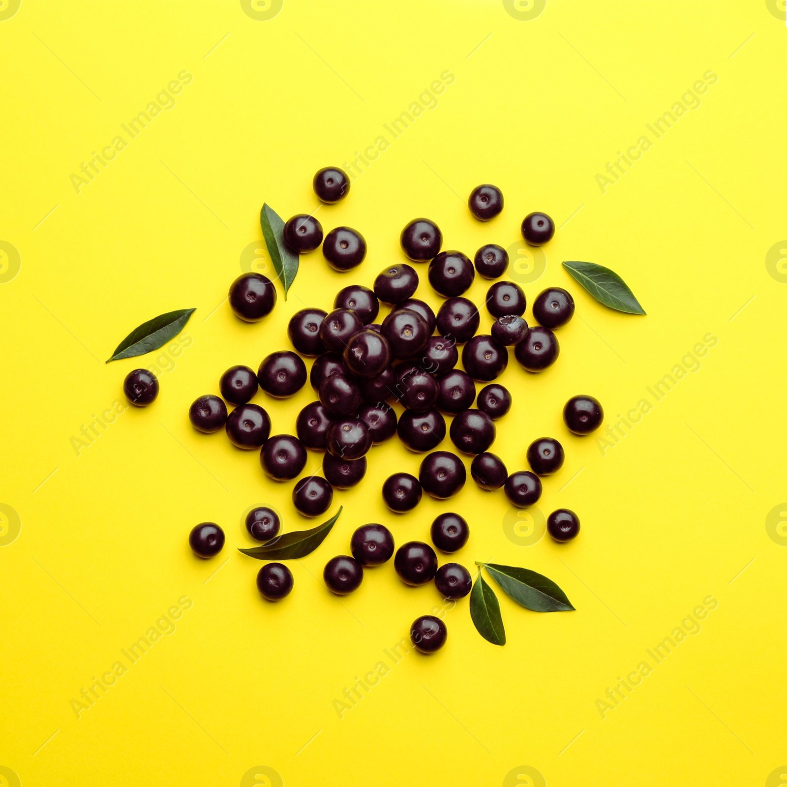 Photo of Fresh acai berries on yellow background, flat lay