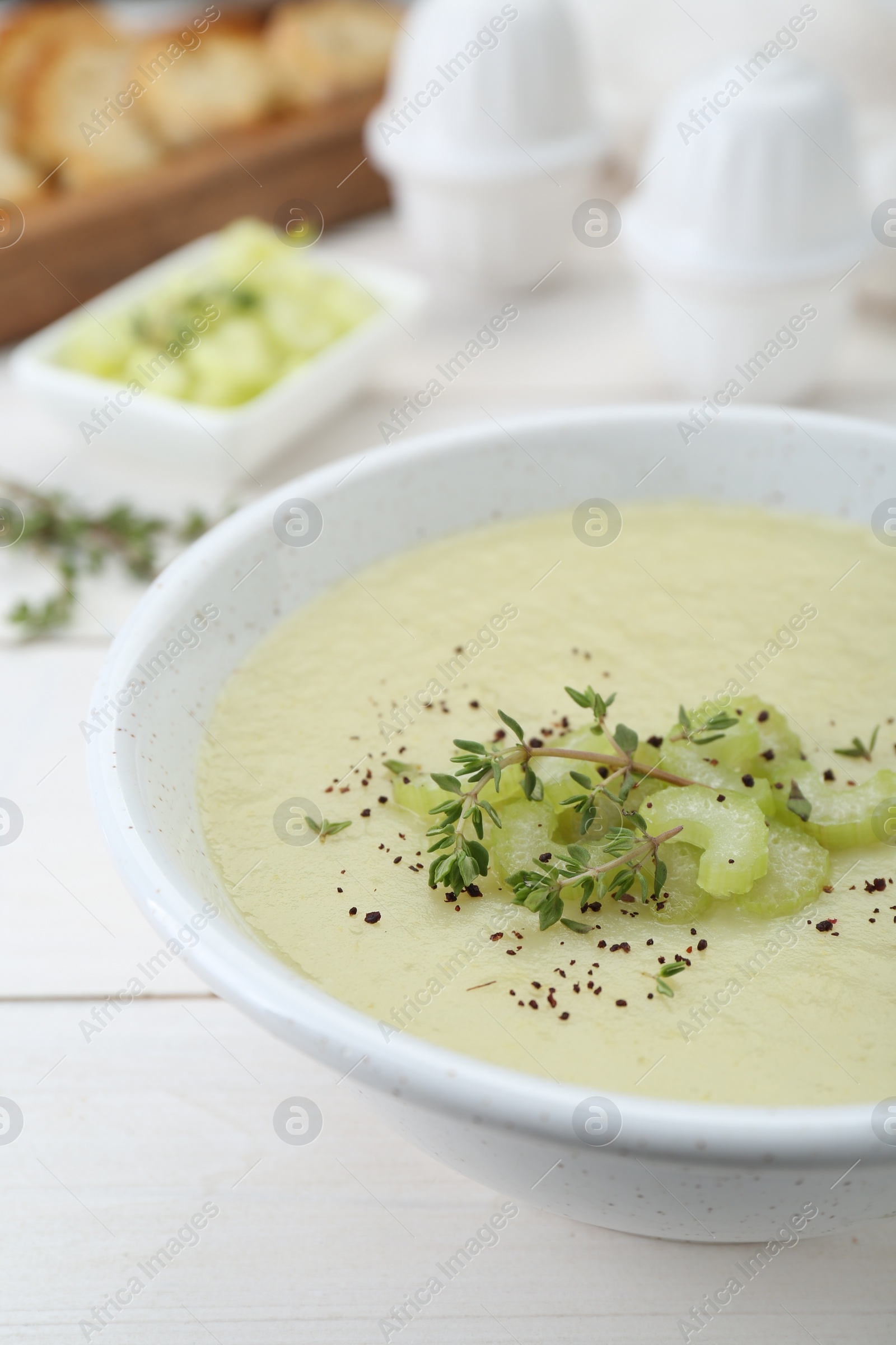 Photo of Bowl of delicious celery soup on white wooden table, closeup