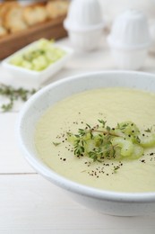 Bowl of delicious celery soup on white wooden table, closeup