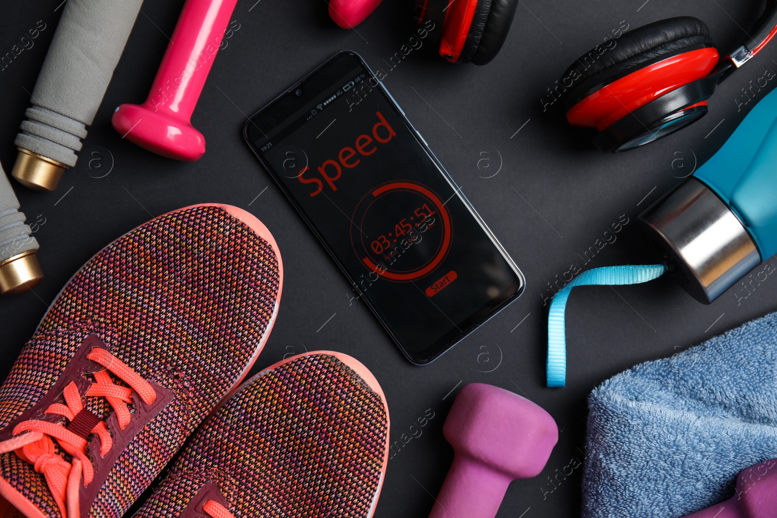 Photo of Flat lay composition with fitness equipment and smartphone on black background