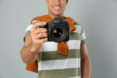 Photo of Professional photographer working on light grey background in studio, focus on camera