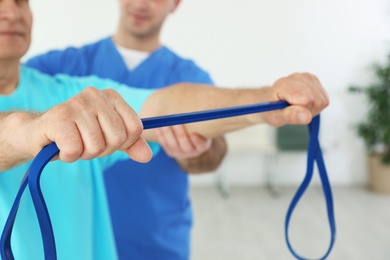 Professional physiotherapist working with senior patient in rehabilitation center, closeup