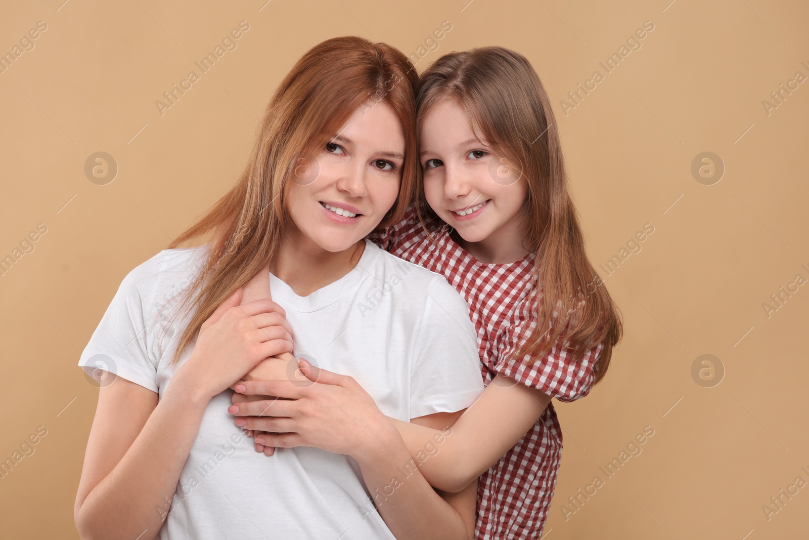 Photo of Portrait of happy mother and her cute daughter on beige background