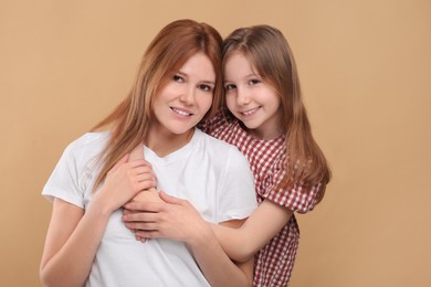 Photo of Portrait of happy mother and her cute daughter on beige background