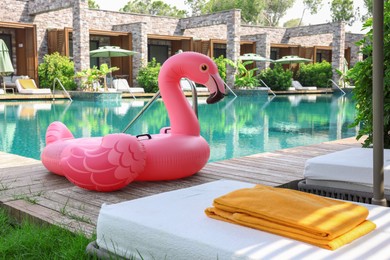 Photo of Float in shape of flamingo on wooden deck near swimming pool and sunbeds at luxury resort