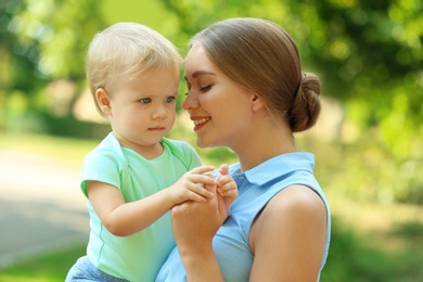 Photo of Young mother with her cute child in green park