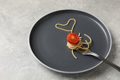 Photo of Heart made of tasty spaghetti, fork and tomato on light grey table