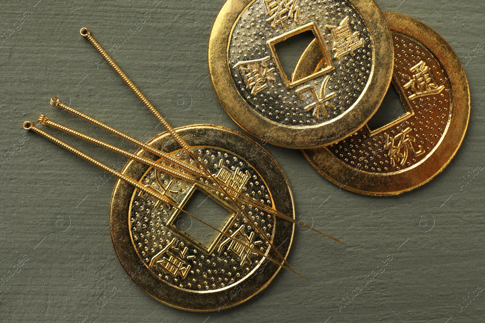 Photo of Acupuncture needles and antique Chinese coins on grey wooden table, flat lay