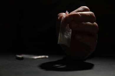 Photo of Drug addiction. Man with plastic bag of cocaine at grey table, selective focus