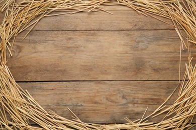 Frame made of dried hay on wooden background, top view. Space for text