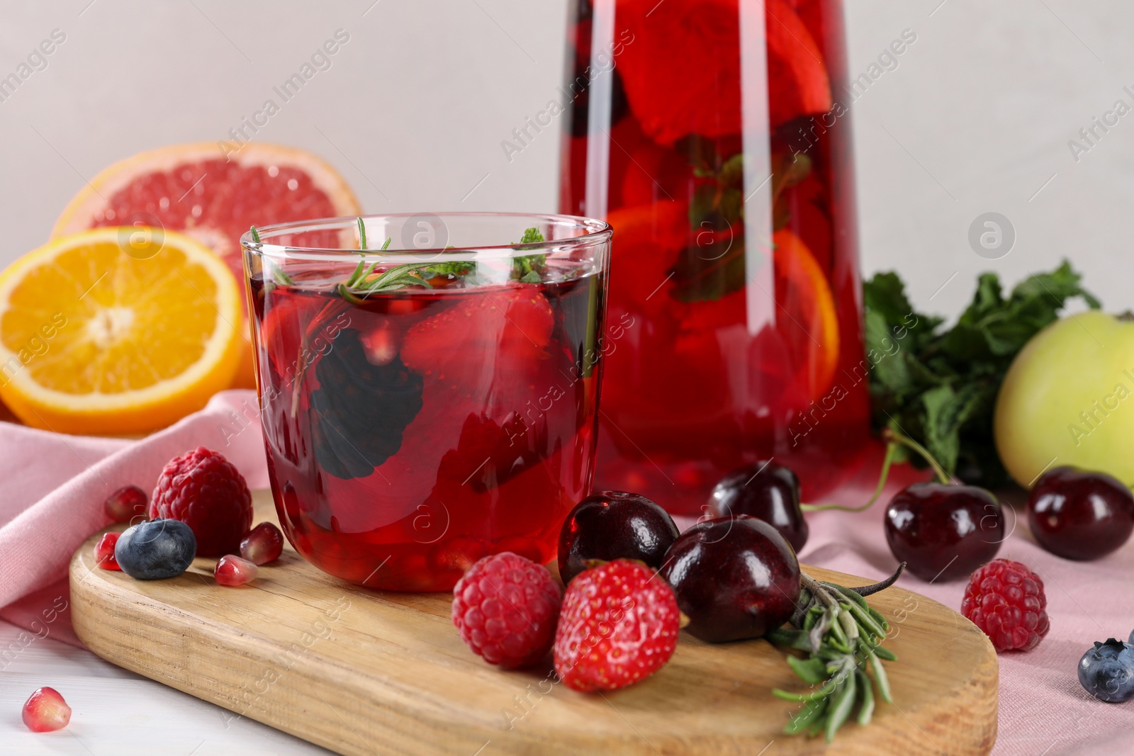 Photo of Glass of delicious sangria, fruits and berries on table, closeup