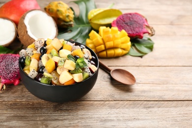 Delicious exotic fruit salad and ingredients on wooden table