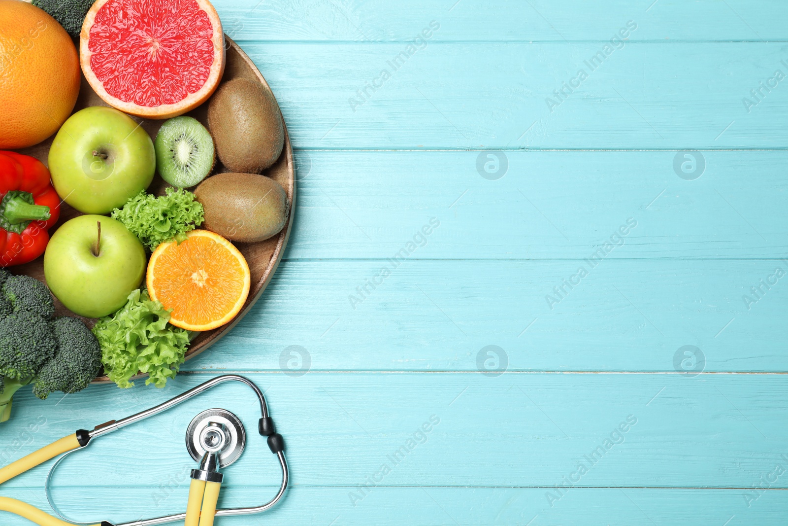 Photo of Fruits, vegetables and stethoscope on light blue wooden background, flat lay with space for text. Visiting nutritionist