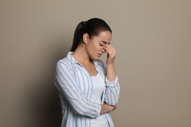 Young woman suffering from headache on beige background