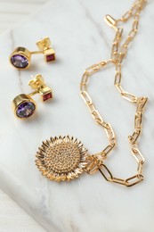 Necklace and earrings on white table, closeup