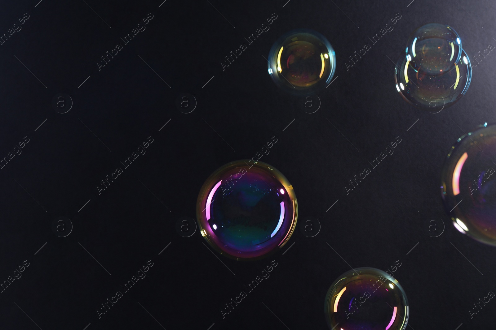 Photo of Beautiful transparent soap bubbles on dark background, space for text