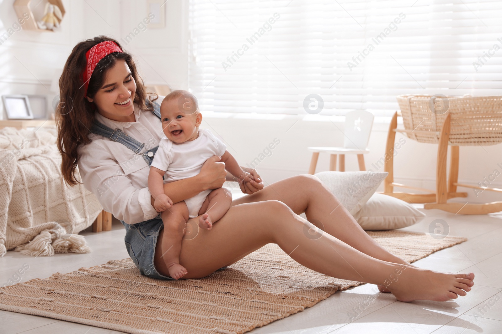 Photo of Happy young mother with her cute baby on floor in bedroom