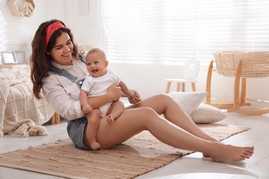 Happy young mother with her cute baby on floor in bedroom