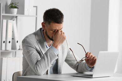 Man suffering from eyestrain at desk in office