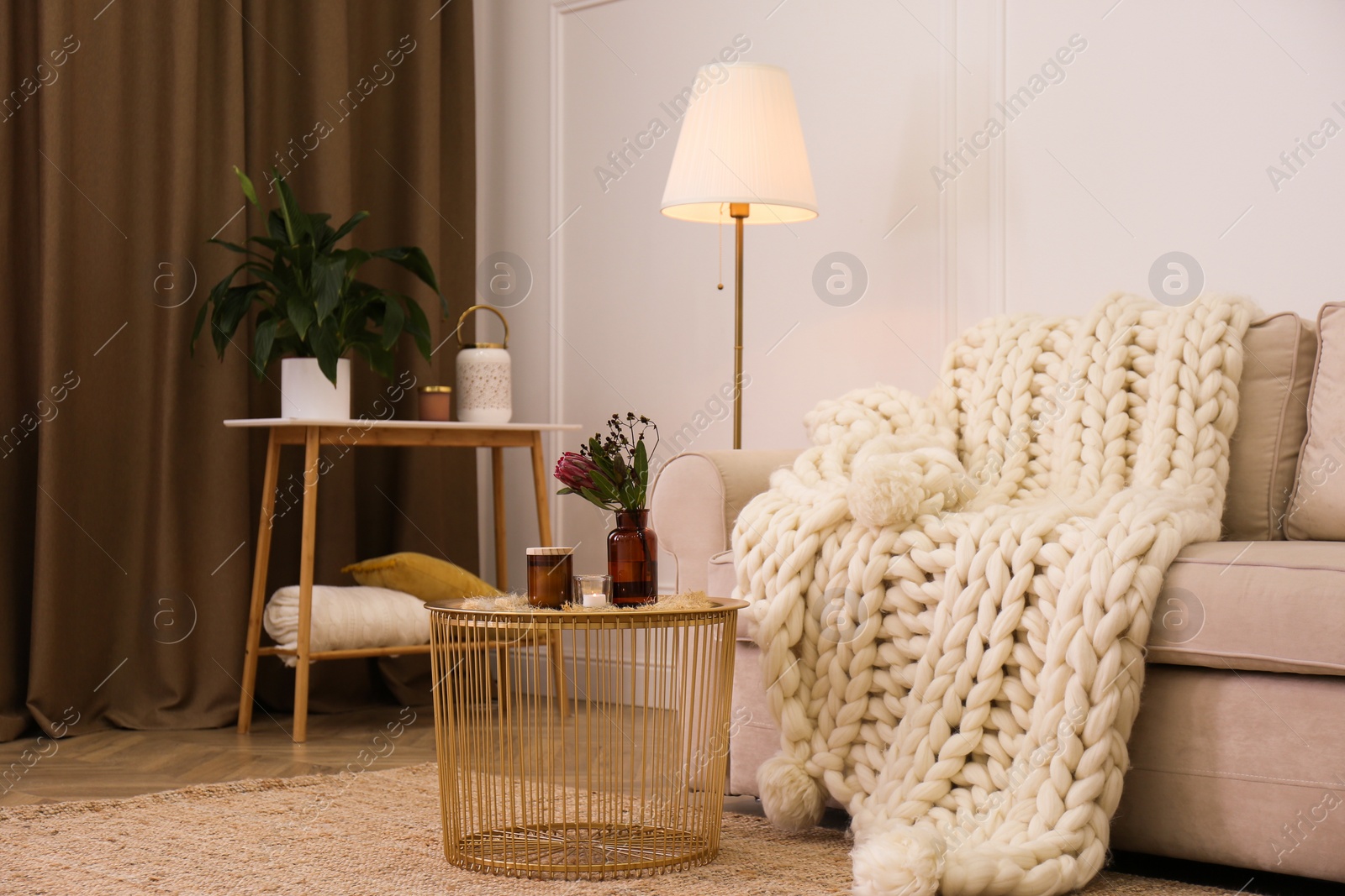 Photo of Soft knitted blanket on couch in living room. Interior element