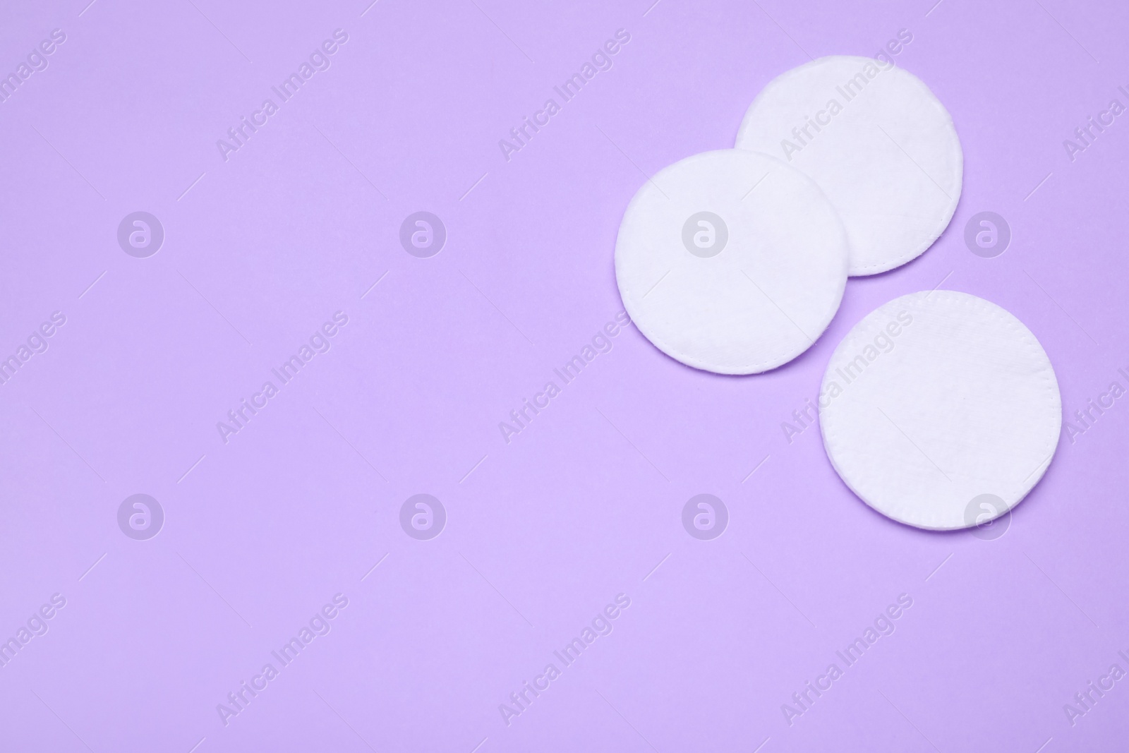 Photo of Cotton pads on lilac background, flat lay. Space for text