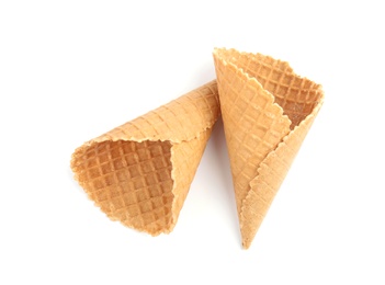 Photo of Empty crispy waffle cones for ice cream on white background, top view