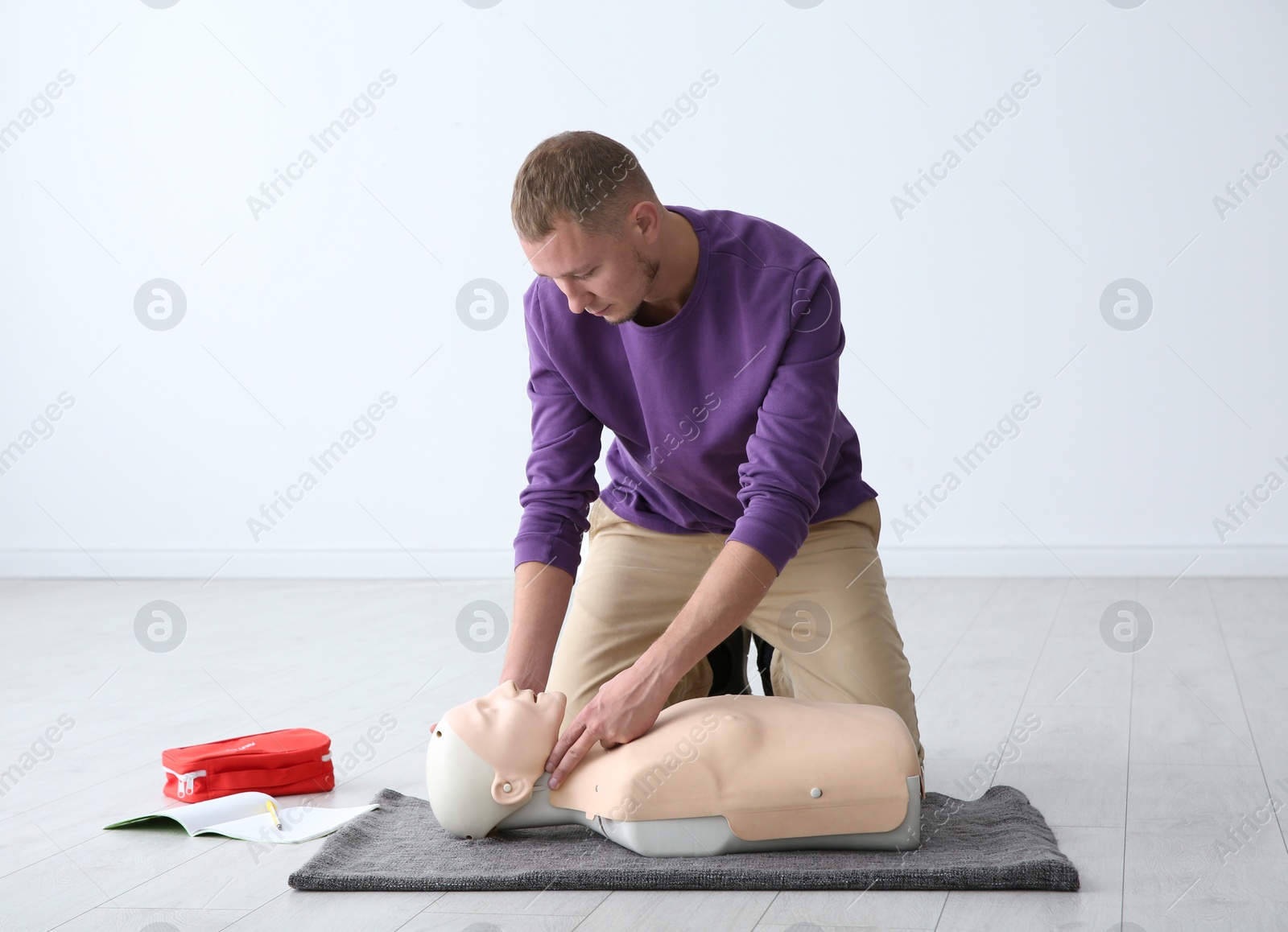 Photo of Man practicing first aid on mannequin indoors