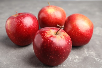 Photo of Ripe juicy red apples on grey table, closeup