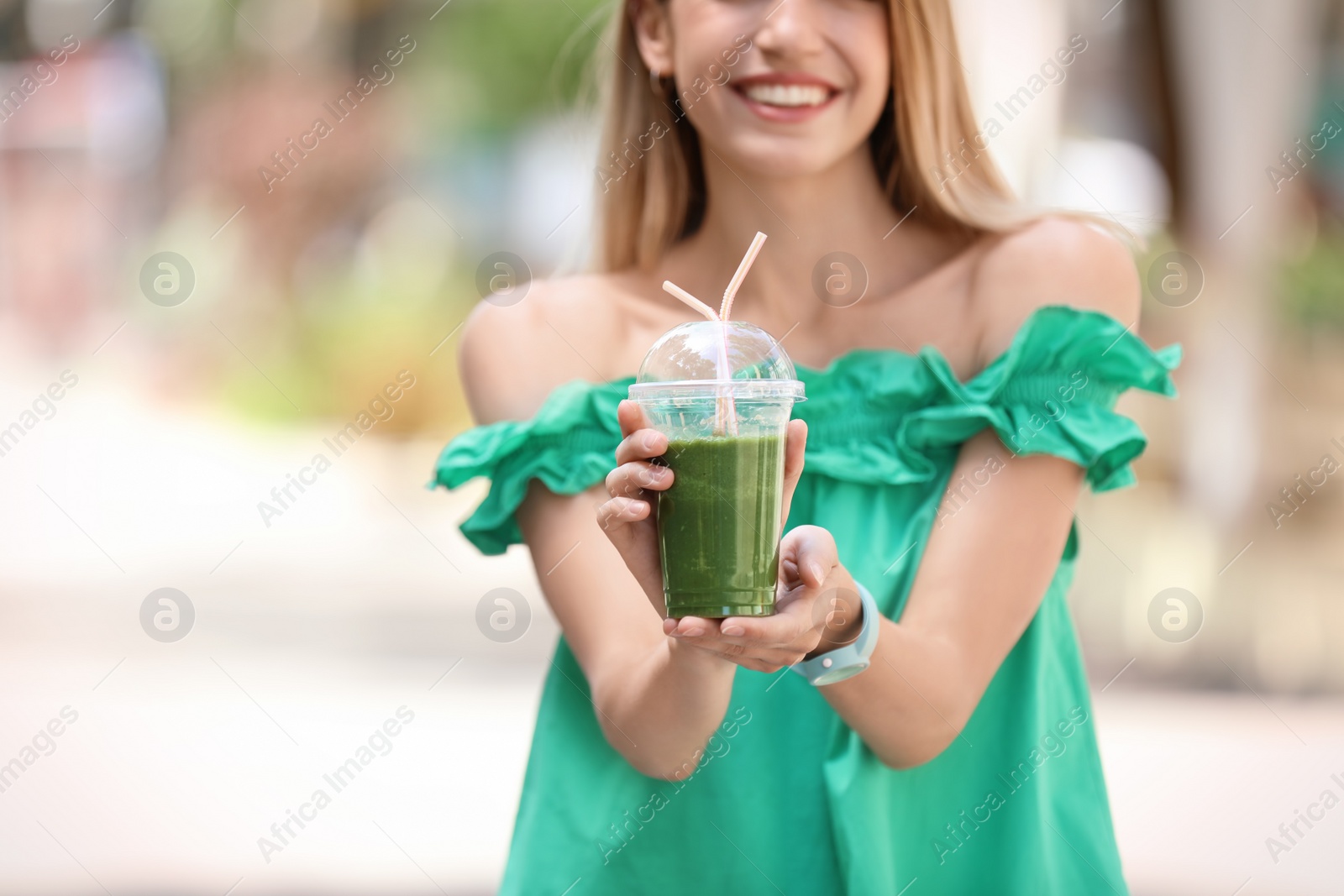 Photo of Young woman with plastic cup of healthy smoothie outdoors