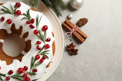 Flat lay composition with traditional Christmas cake and decorations on light grey table, closeup. Space for text