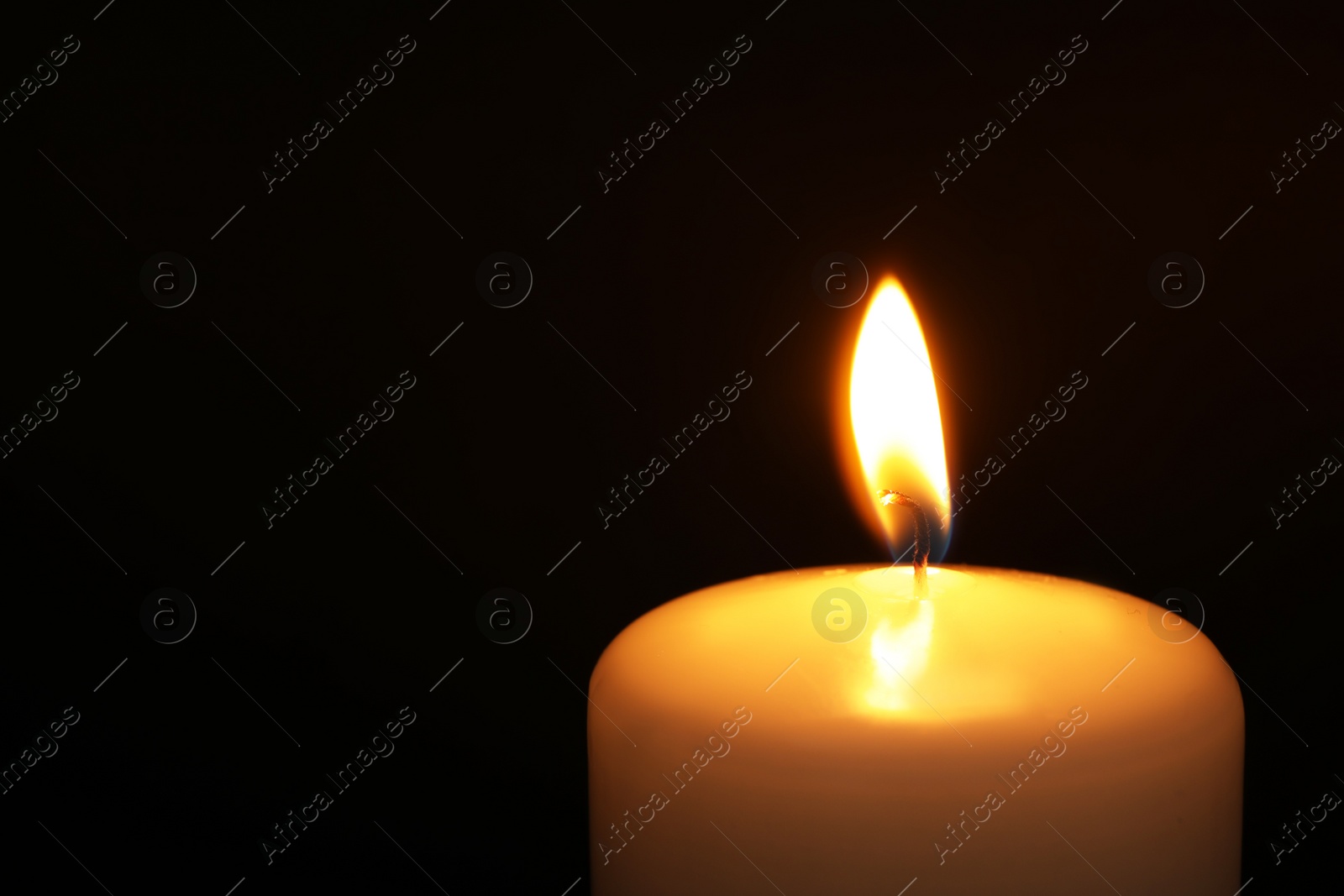 Photo of Burning candle on dark background, closeup with space for text. Symbol of sorrow