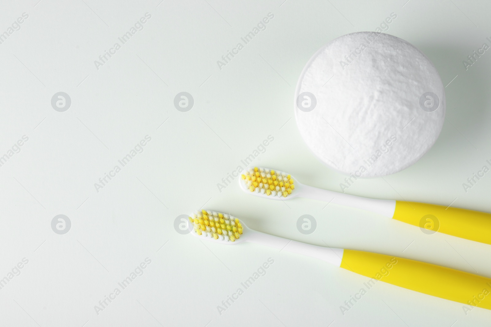 Photo of Toothbrushes and bowl with baking soda on beige background, flat lay. Space for text
