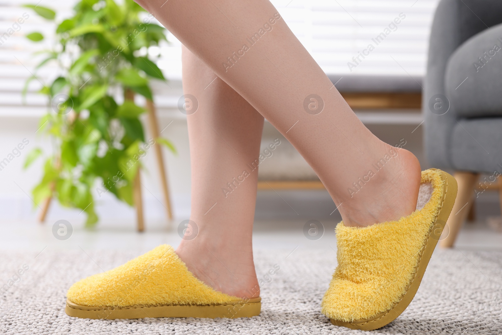 Photo of Woman in yellow soft slippers at home, closeup