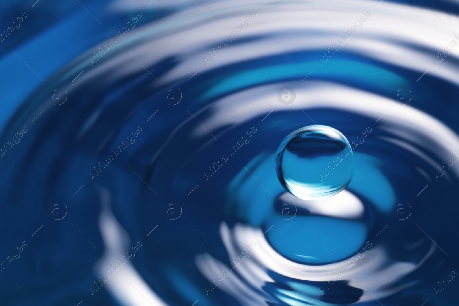 Photo of Splash of clear water with drop on blue background, closeup