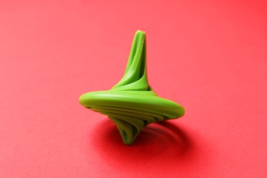 Photo of One green spinning top on red background, closeup