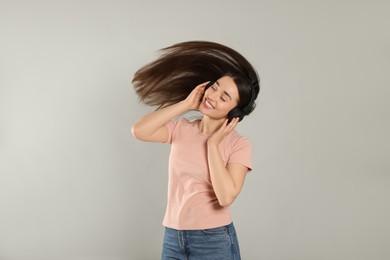 Photo of Happy woman in headphones listening music and dancing on grey background