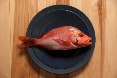 Photo of Fresh raw fish on wooden table, top view