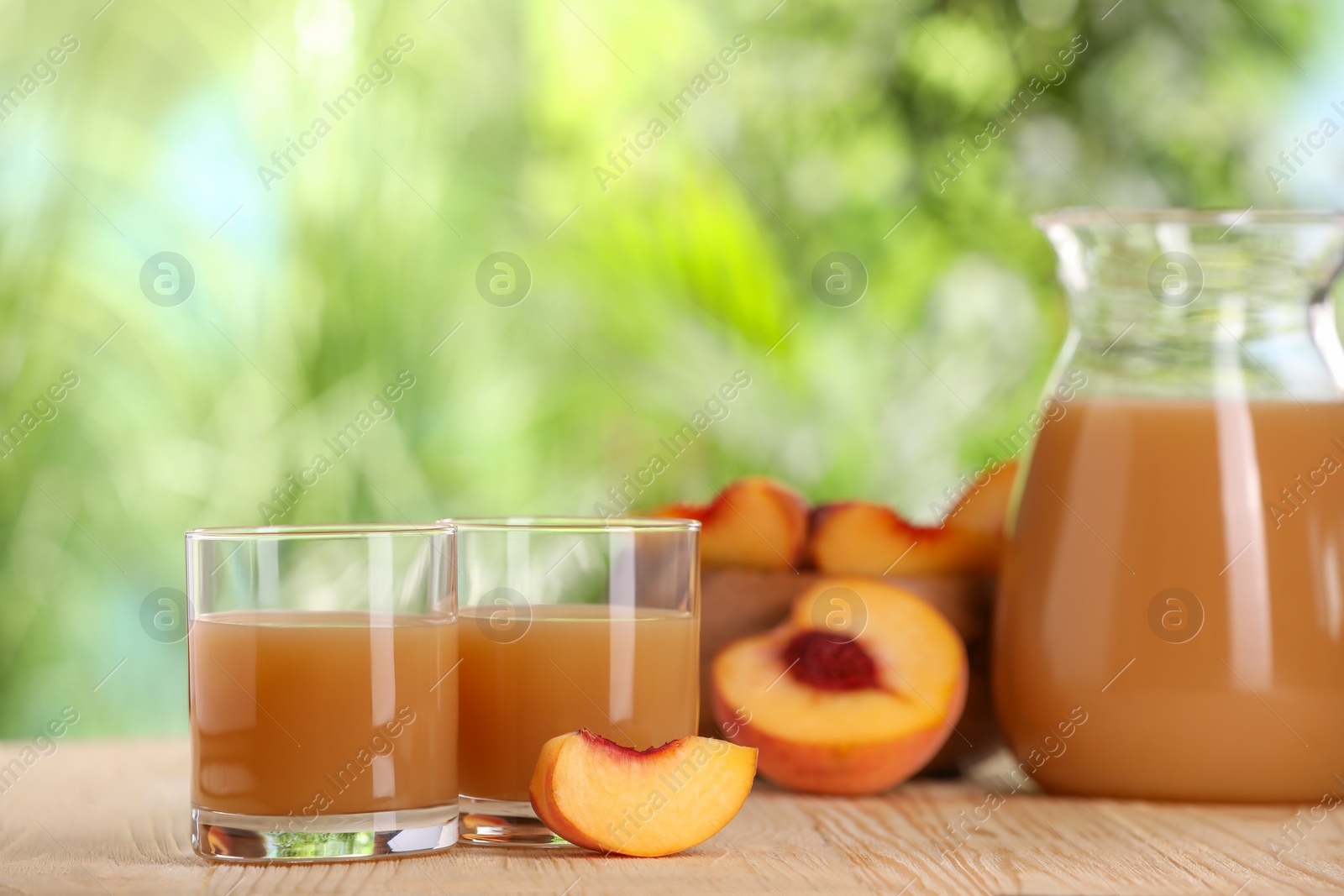 Photo of Tasty peach juice and fresh fruits on wooden table outdoors, space for text