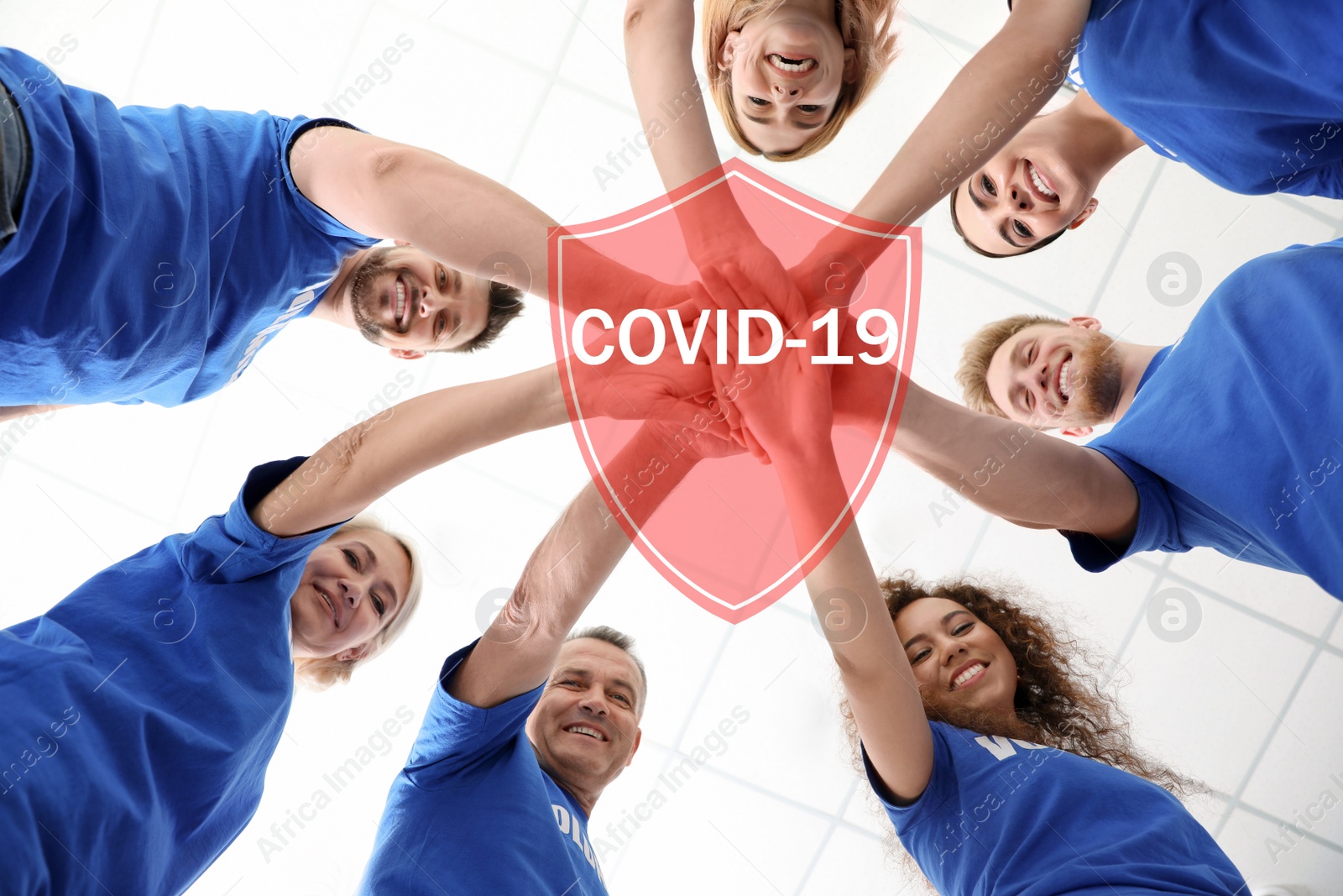 Image of Volunteers uniting to help during COVID-19 outbreak. Group of people holding hands together on light background, shield illustration