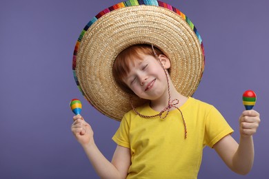 Photo of Cute boy in Mexican sombrero hat dancing with maracas on white background