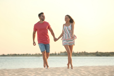 Photo of Happy young couple walking together on beach